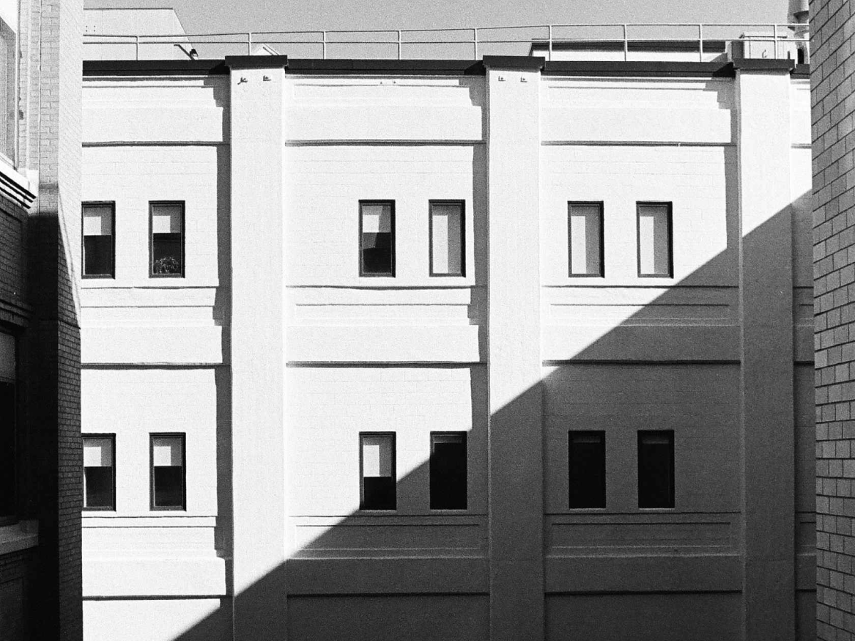 Shot of turn of the century high-rise building with bright white sunlight and high contrast black shades.