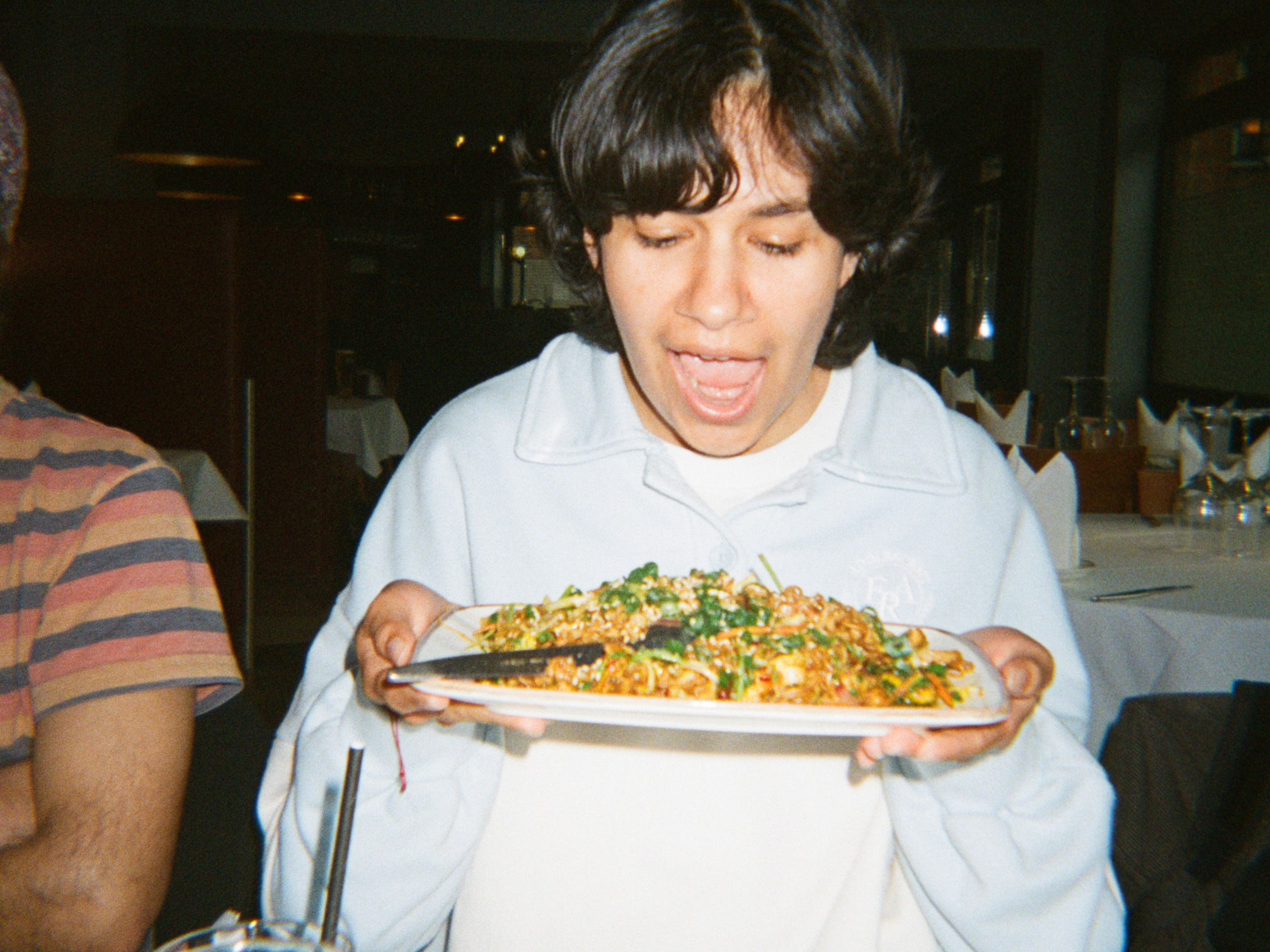 Person holding a plate of food in an indoor setting - shot on PURE 35 film camera