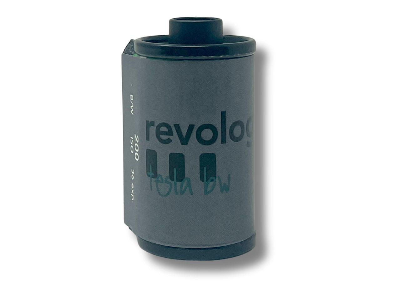 Dark grey 35mm film cassette with 'revolog tesla bw' branding on a white background.