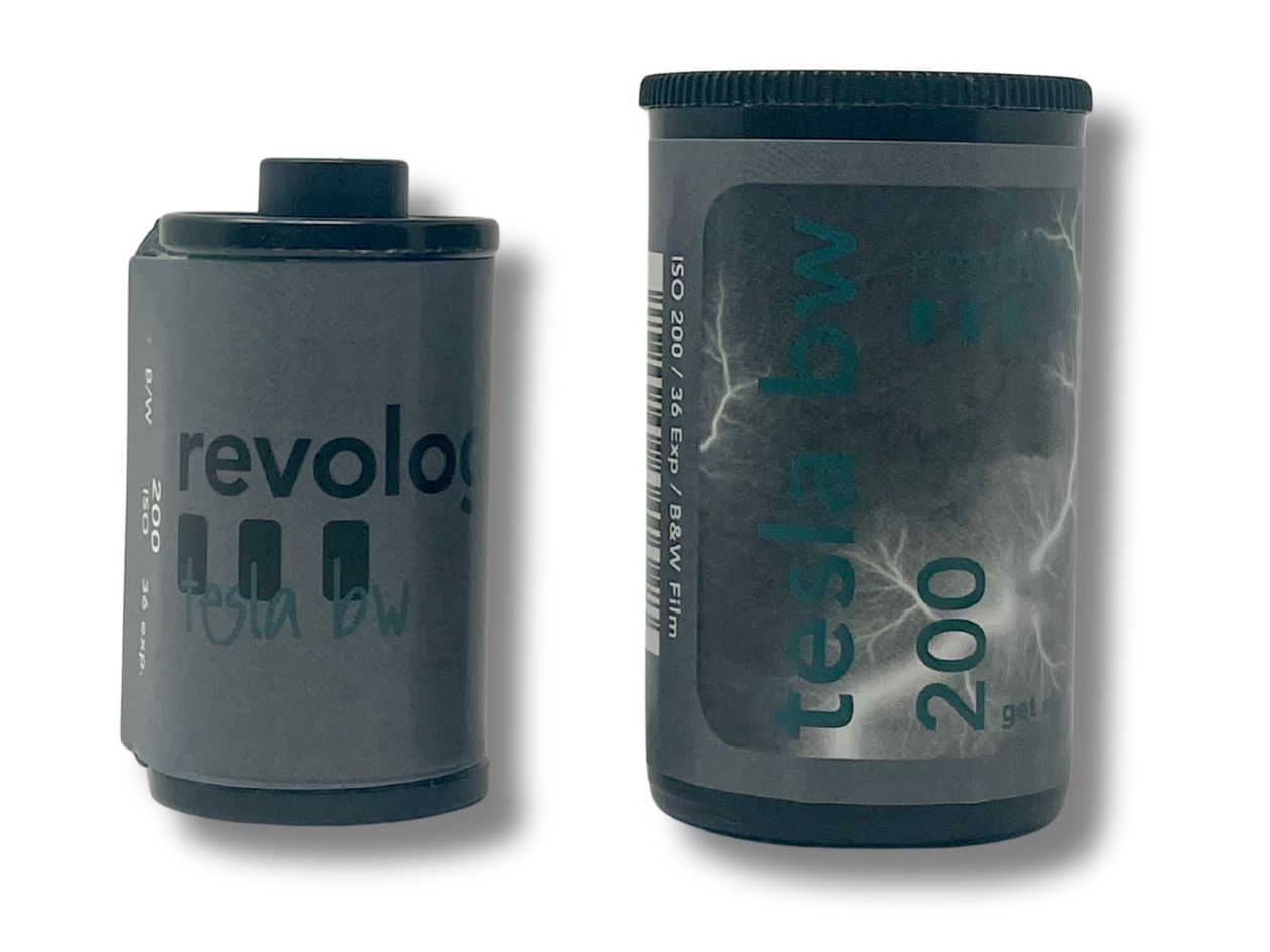 Dark grey 35mm film cassette with 'revolog tesla bw' branding and a plastic black film pot with the same branding, on a white background.