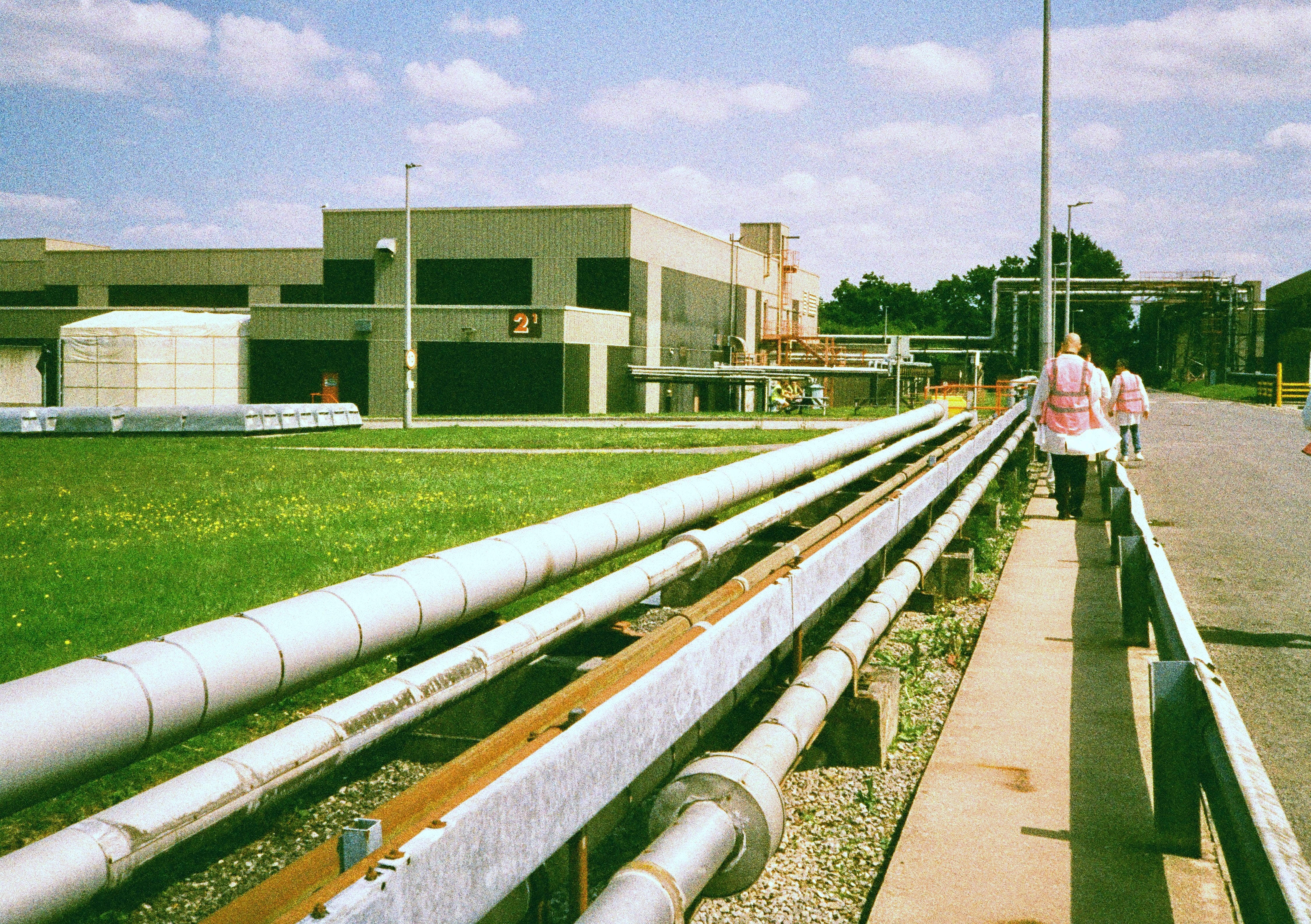 Long white pipes on a concrete path with a building in the background - shot on Harman Phoenix II 35mm film