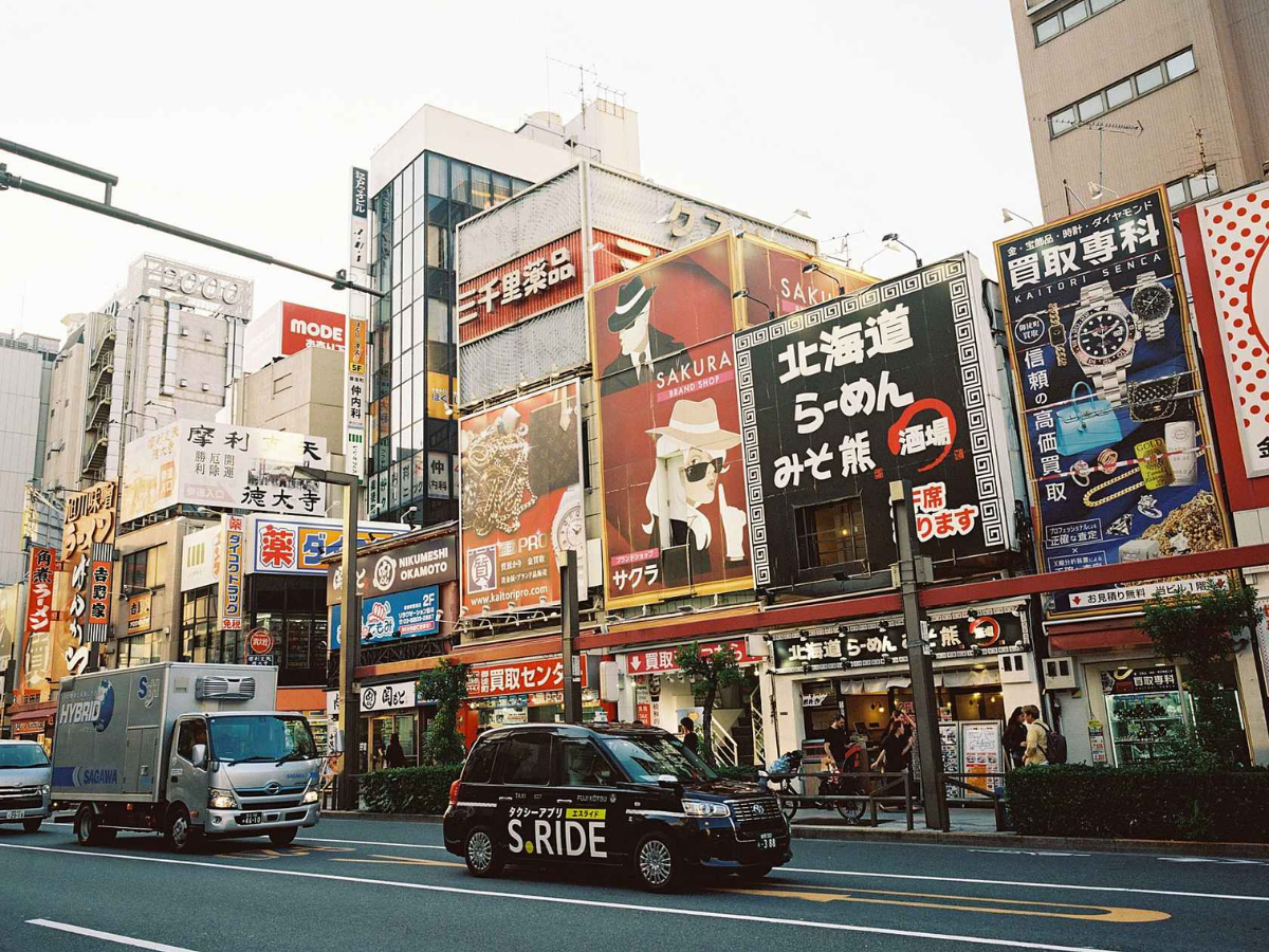 Busy street scene in an urban area with colorful billboards and vehicles.