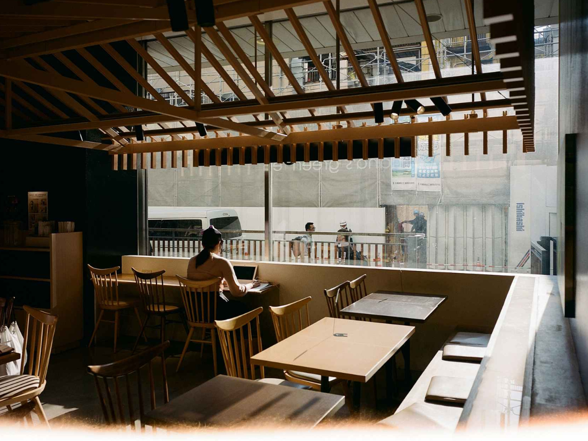 Person sitting at a table in a modern cafe with large windows