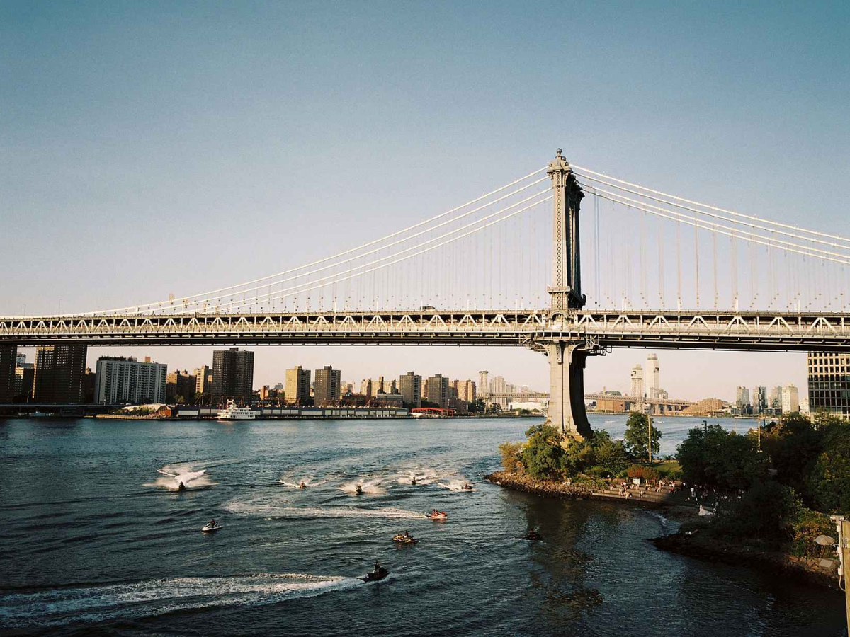 Manhattan Bridge over the East River with boats and city skyline in the background