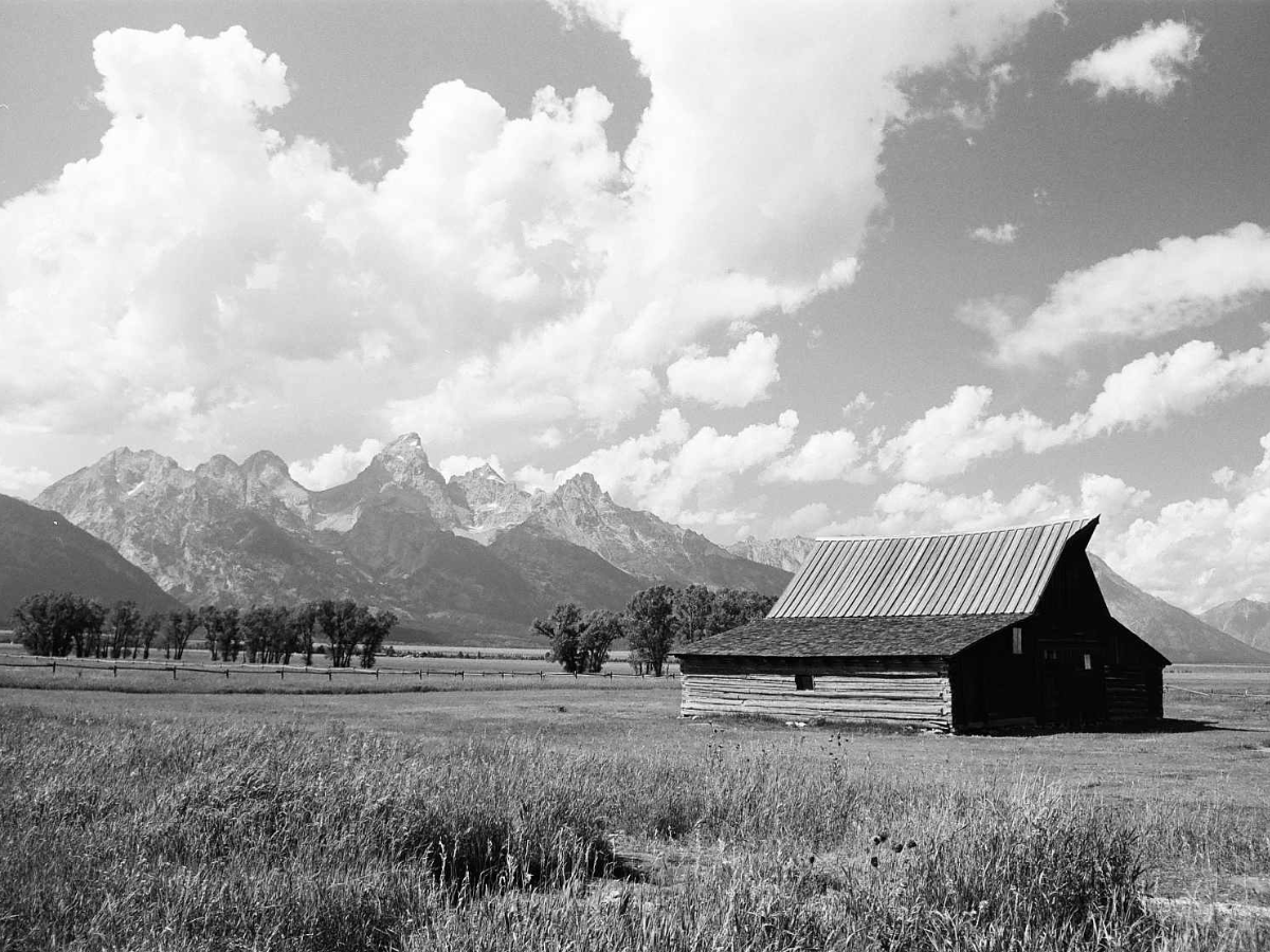Barn in a field with mountains and clouds in the background