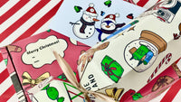 Festive wrapping paper with candy canes, gifts, and snow globes, alongside a Christmas card featuring a snowman and penguin in Santa hats. A "Merry Christmas!" gift box with a ribbon sits on a red-and-white striped background.