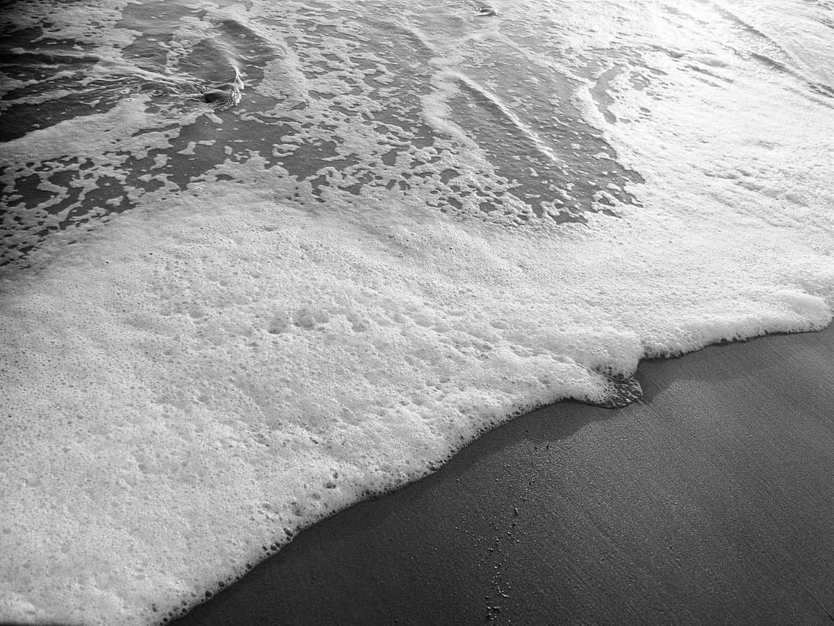 Close-up of ocean waves crashing onto a sandy beach