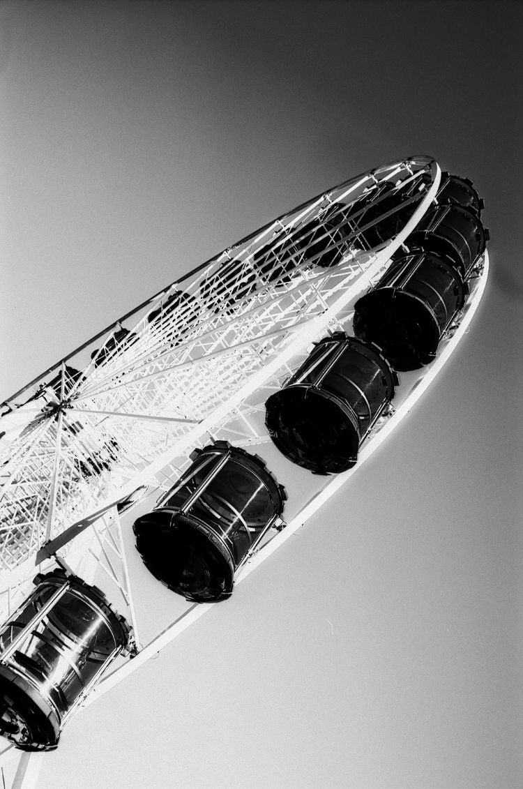 Black and white image of a Ferris wheel against a clear sky.