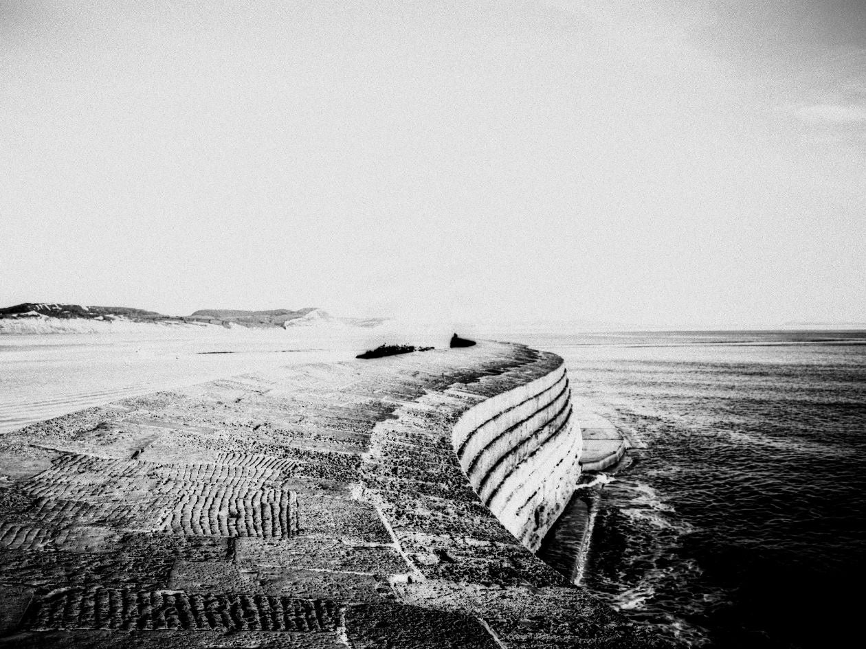 Black and white photograph of a shipwreck on a beach with a clear sky.