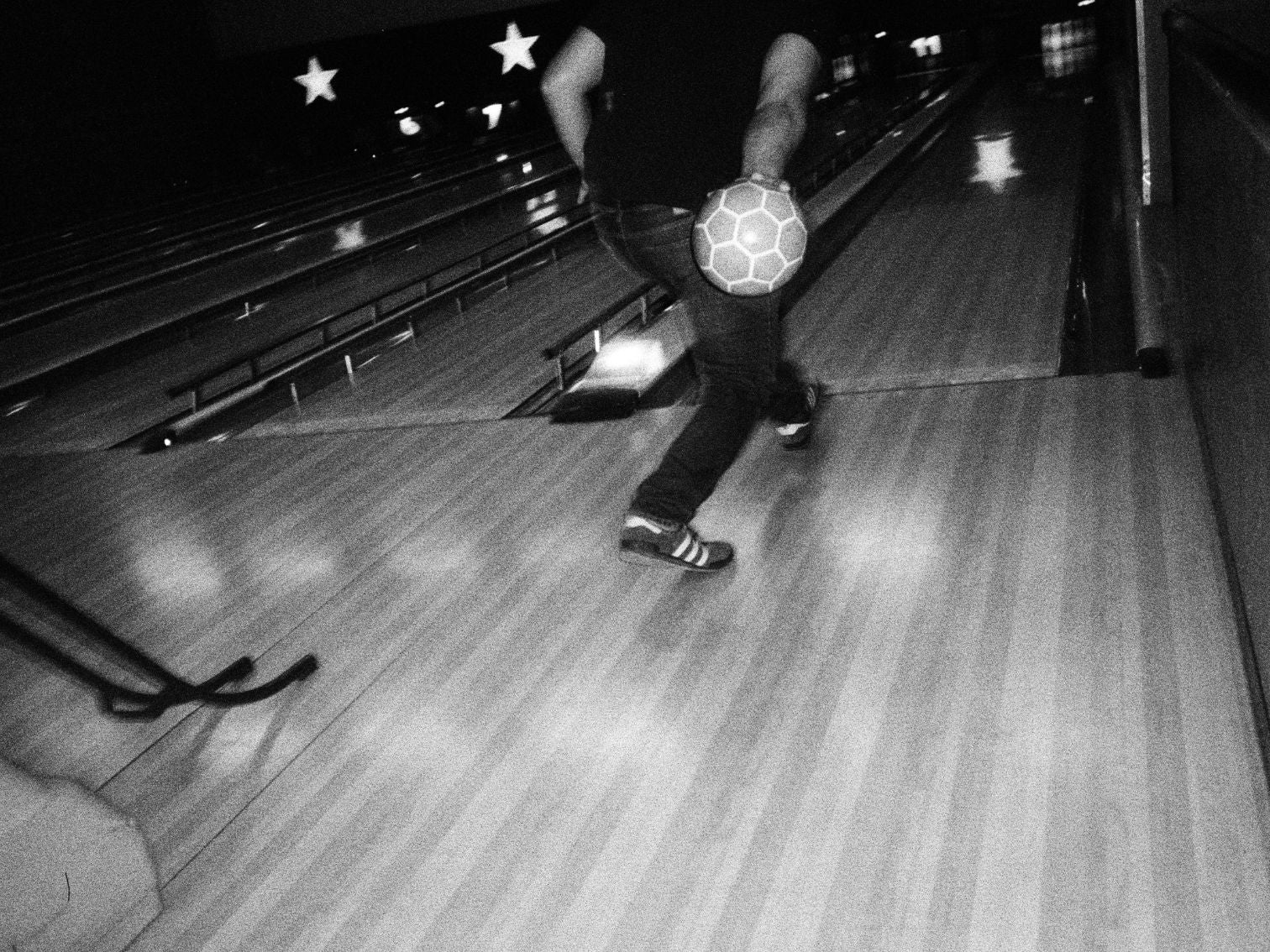 A dynamic shot of a person about to bowl, captured mid-motion on a bowling lane.