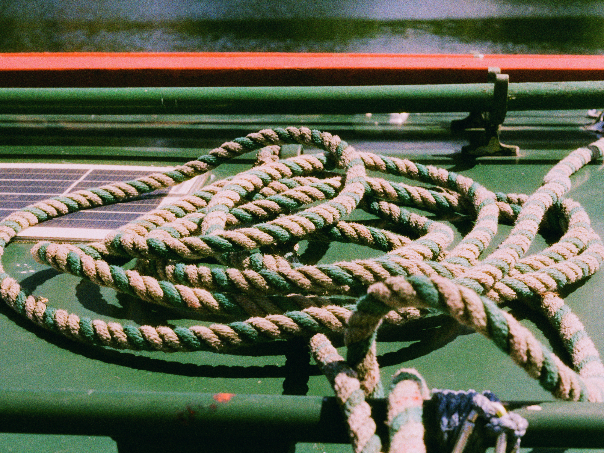 Coiled green and beige rope on a metal surface with water in the background - shot on Harman Phoenix 2