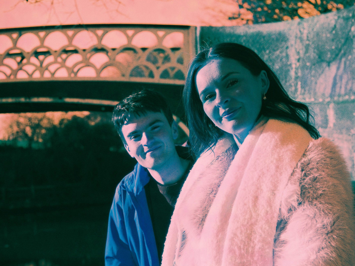 Sample shots (c) Neil Hibbs. Two people near a bridge smiling to the camera.