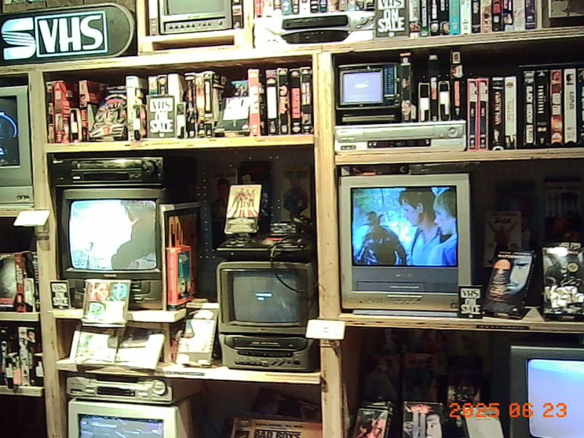 Sample Image | Vintage VHS tapes and electronic devices displayed on shelves.