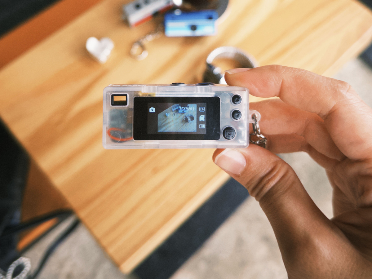 Small Charmera camera held by a hand with a blurred background