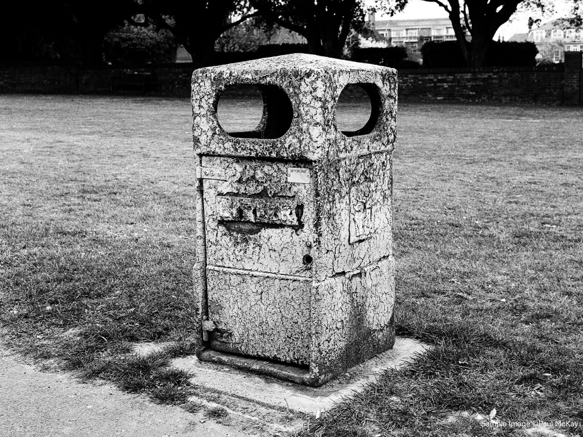 Worn-out trash bin in a grassy area