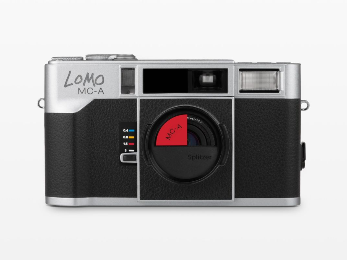 A Lomo MC-A Splitter camera with a black textured leatherette body, silver metal casing, and a distinctive red-and-black circular lens element, shown against a plain white background.