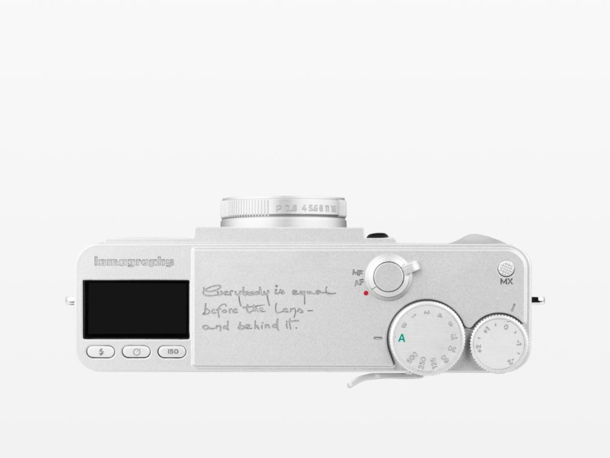 A silver rangefinder camera with custom handwritten text on its body, shown from a top-down view against a plain white background.