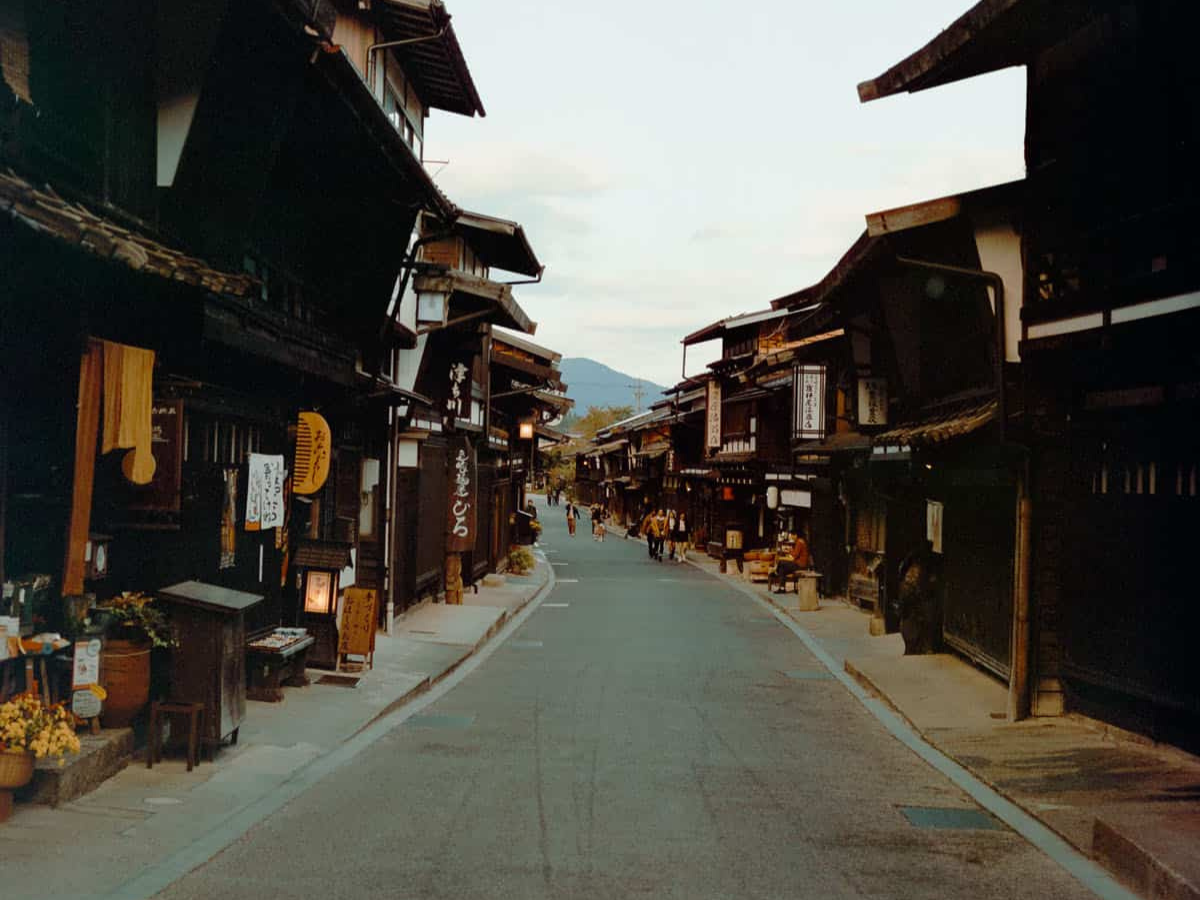 Traditional Japanese street with wooden buildings and people walking. (c) Sample Photos by @notmegapixels