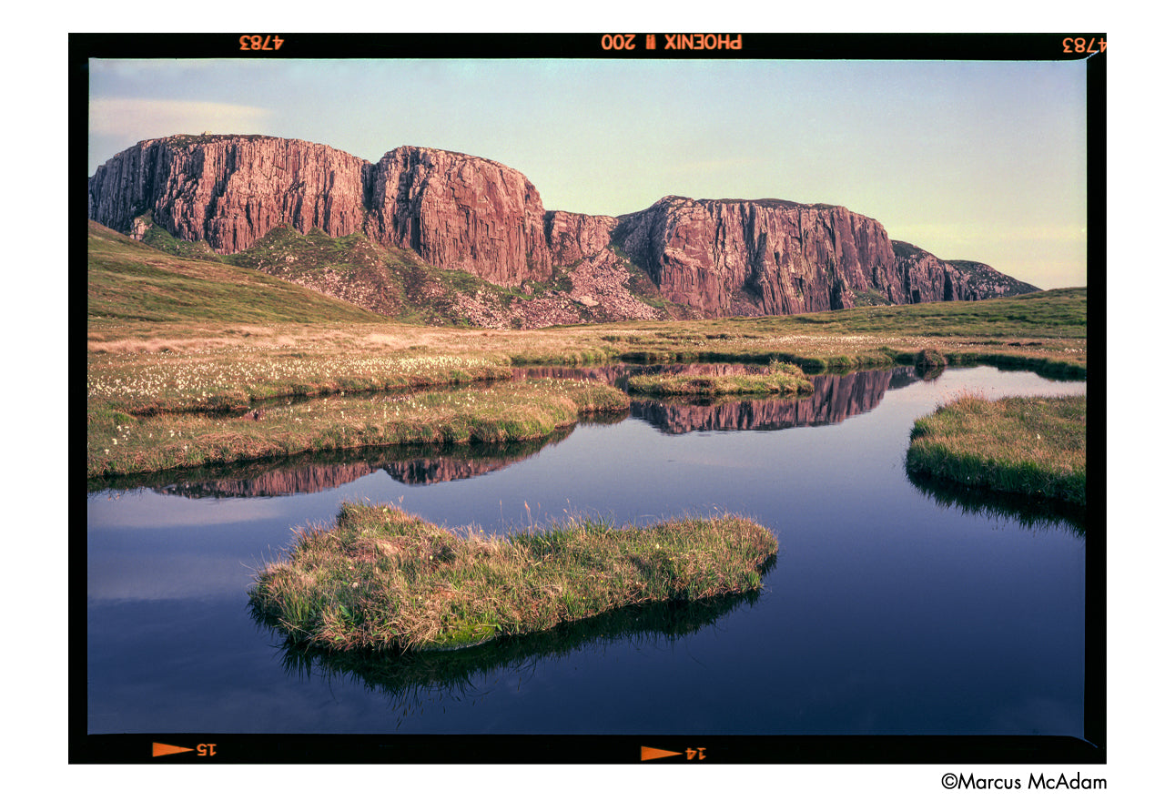 Scenic landscape with cliffs reflected in a calm body of water - shot on Harman Phoenix II 120 film