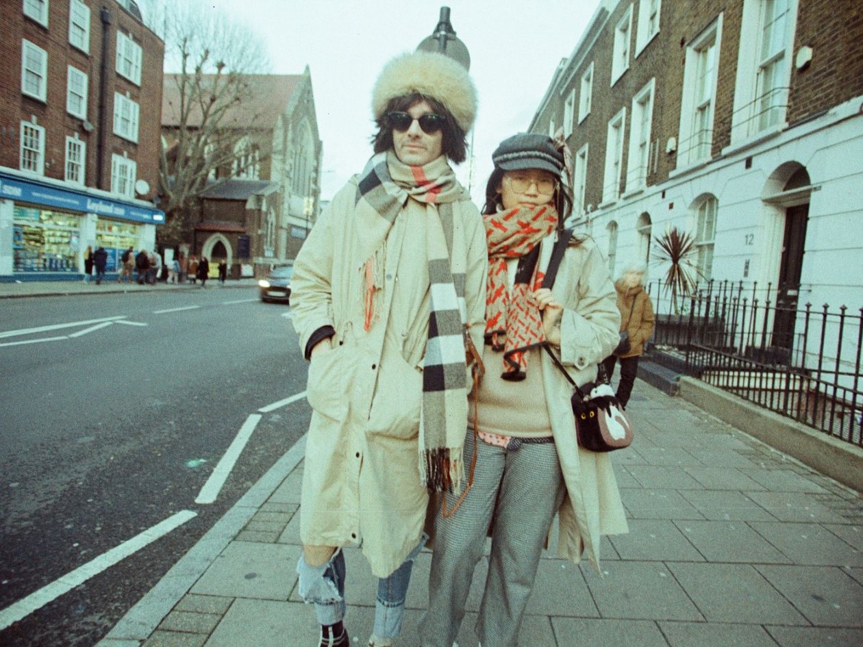 Two people walking on a city street, bundled up in winter clothing.