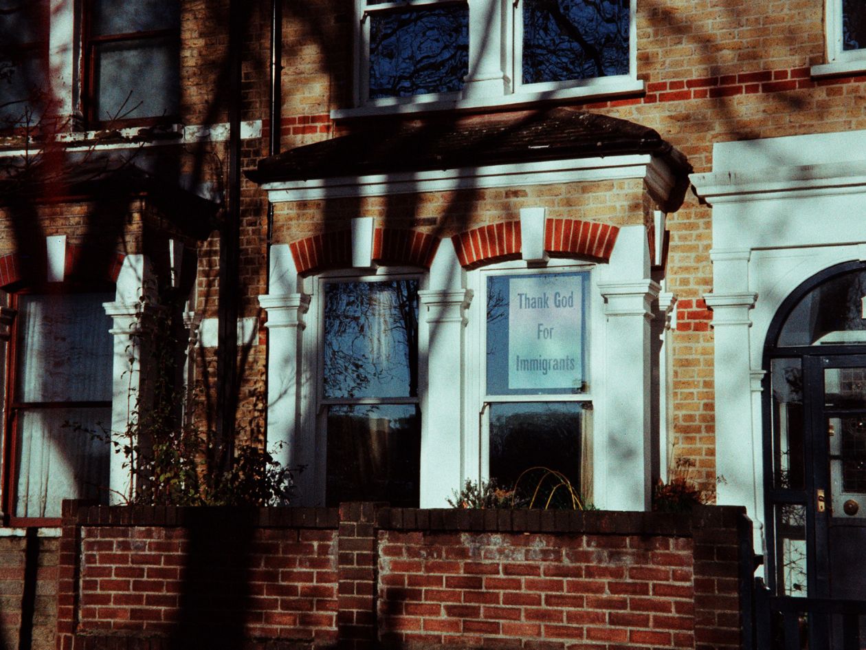 Brick building with a sign in the window, possibly in a residential area.