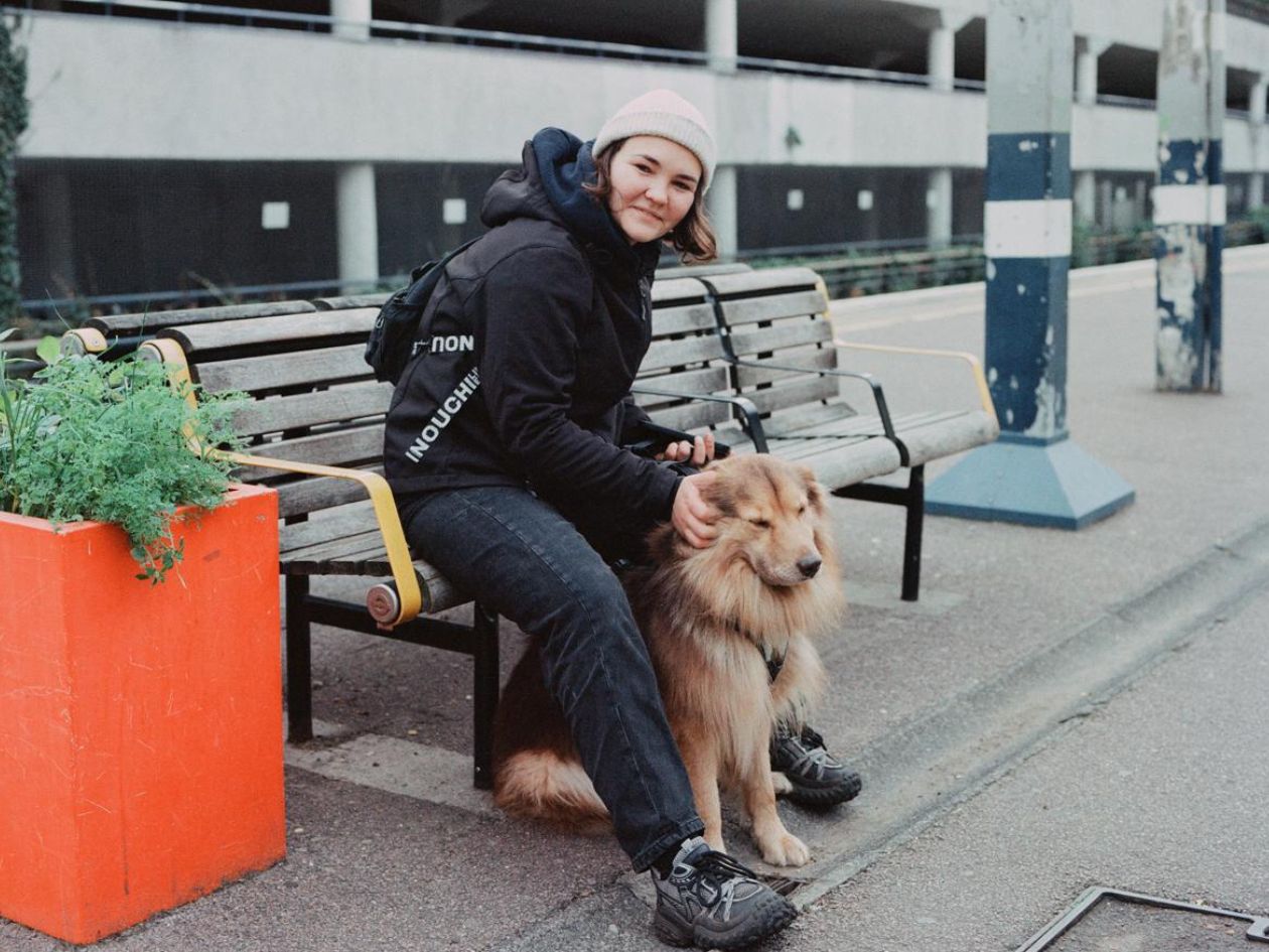 Person sitting on a bench with a dog in an urban setting.