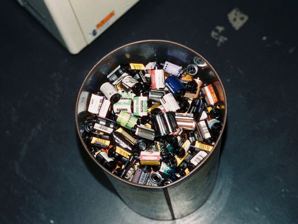 Collection of various 35mm film canisters in a metal container on a dark surface.