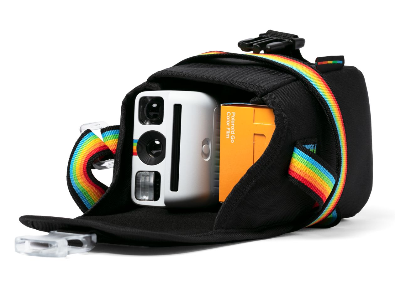 Black camera case with rainbow straps containing a Polaroid Go camera and film on a white background.