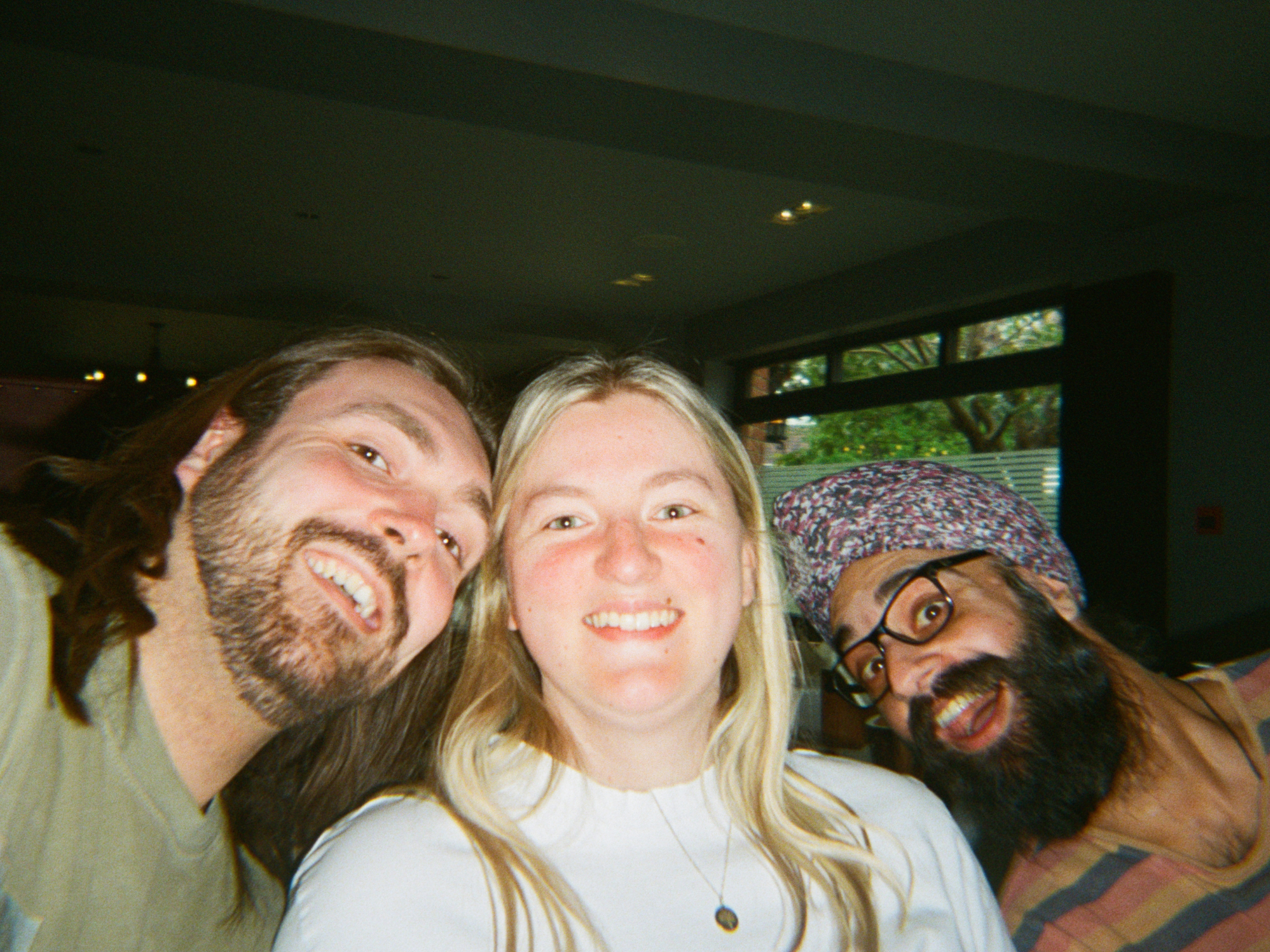 Three people posing together indoors with a window in the background - shot on PURE 35 film camera
