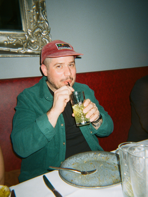 Man drinking from a glass in a restaurant setting - shot on PURE 35 film camera