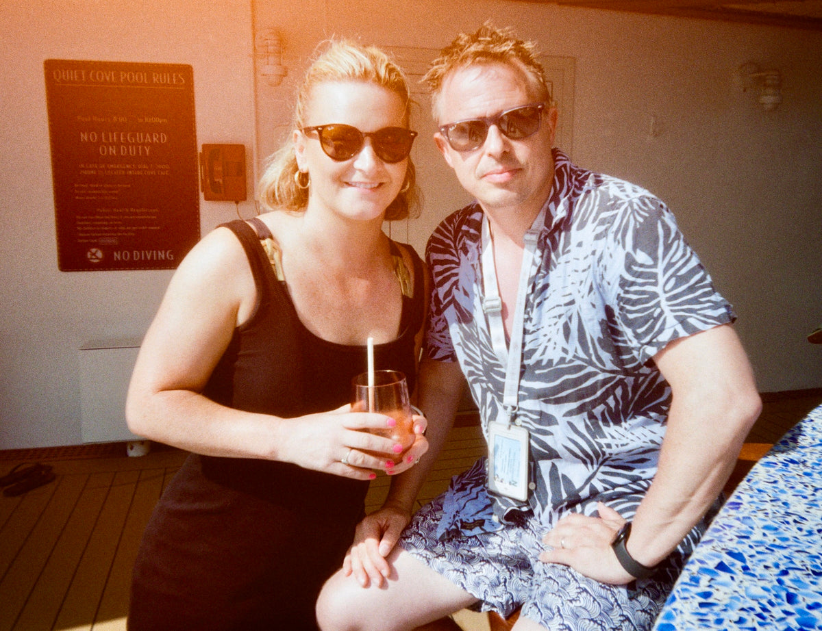 Sample photo for the Kodak EC35 film camera. A man and a woman posing together on a pool deck, wearing sunglasses and tropical shirts. The woman holds a cocktail in a glass with a straw.