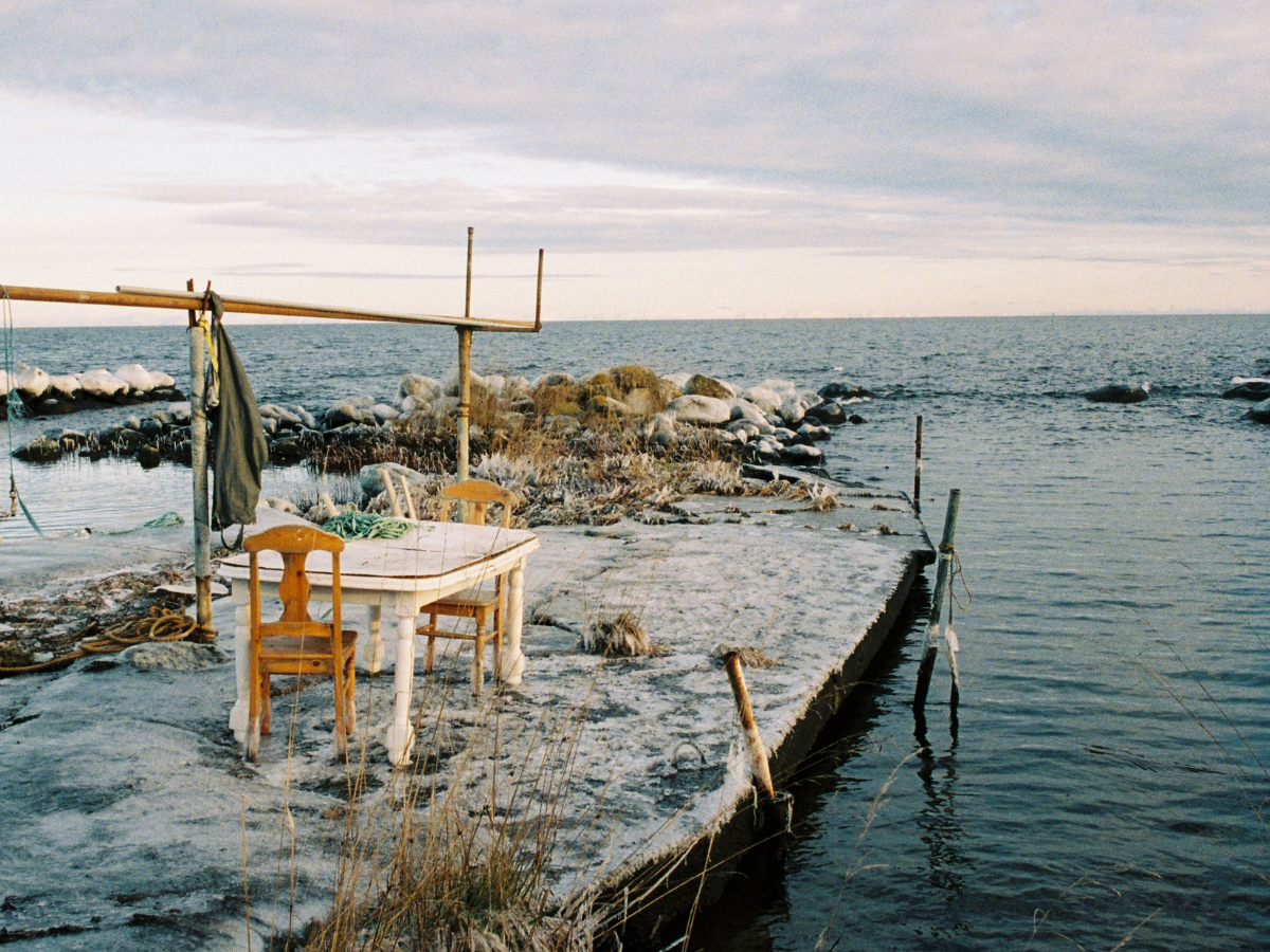 Table and chairs on a dock by the water with a cloudy sky.