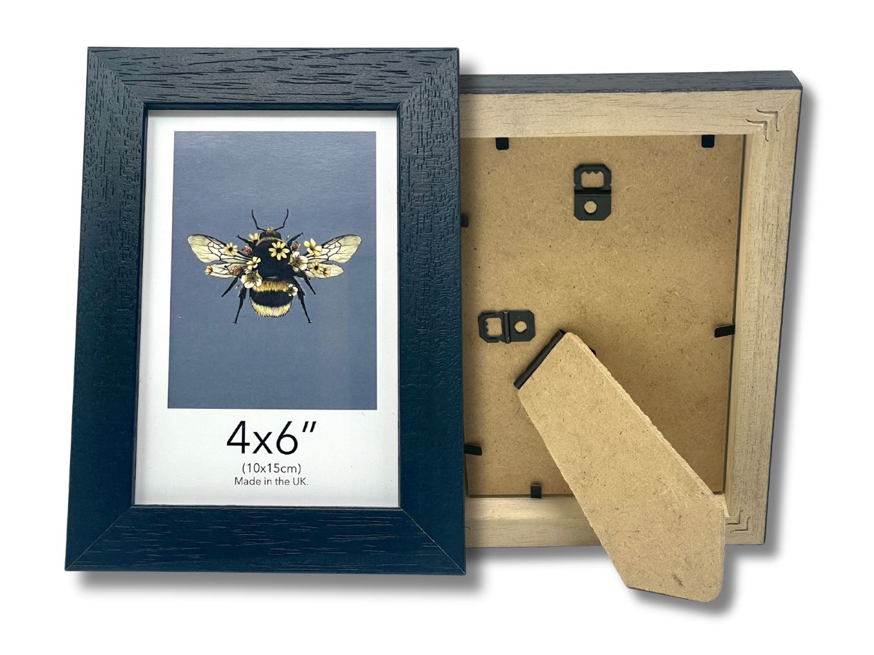 Framed artwork of a bee on a blue background with a cardboard backing, black 4x6" frame.