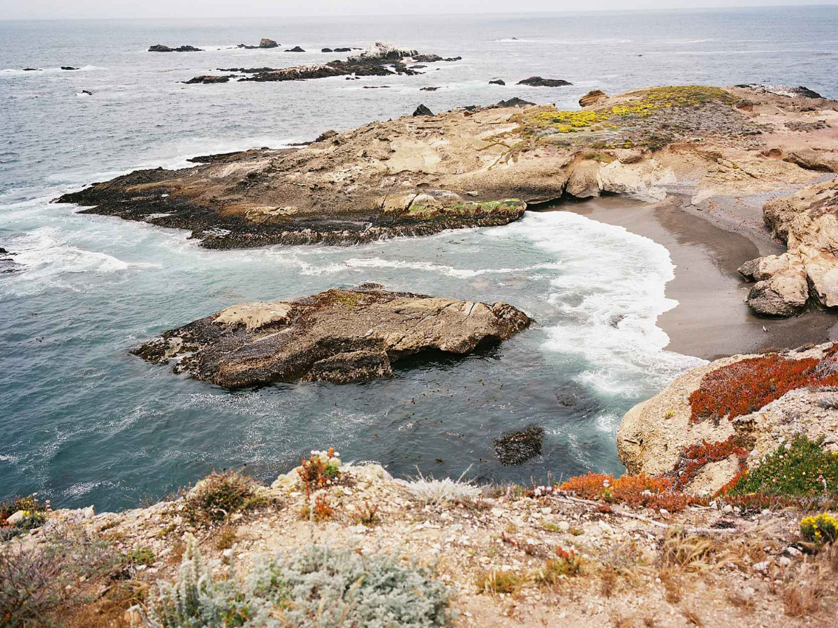 Coastal landscape with rocky outcrops and ocean waves.